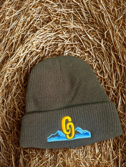 Black beanie with embroidered logo on a straw background