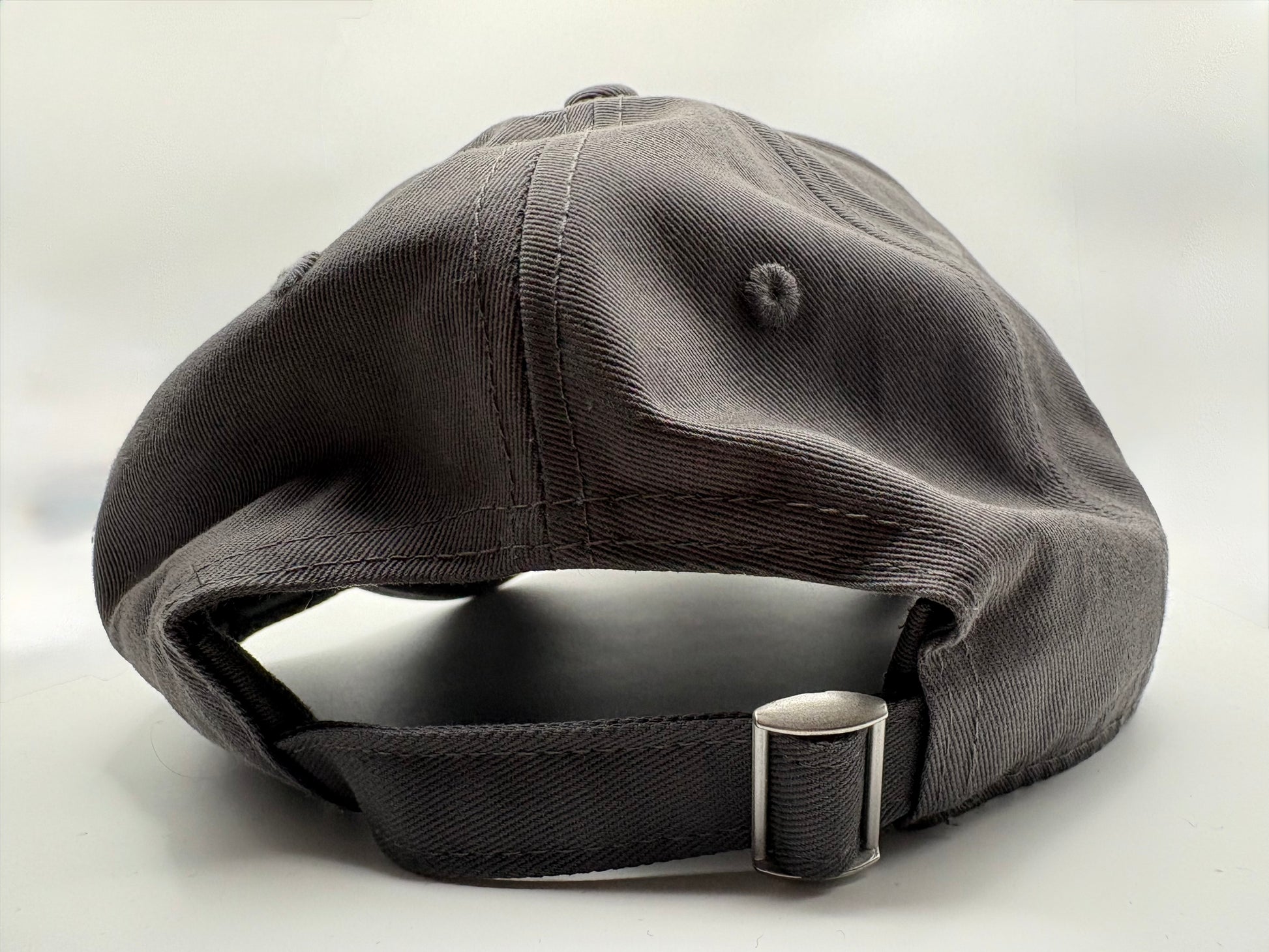Dark gray cap with a metal buckle on a light gray background  rear view.